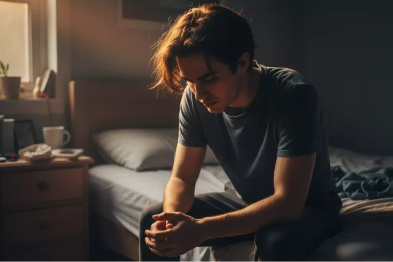 Young adult sitting on the edge of a bed in a dimly lit room, looking down with emotional fatigue, warm sunlight contrasting with shadows