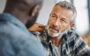 Counselor supporting male patient during opioid addiction treatment.