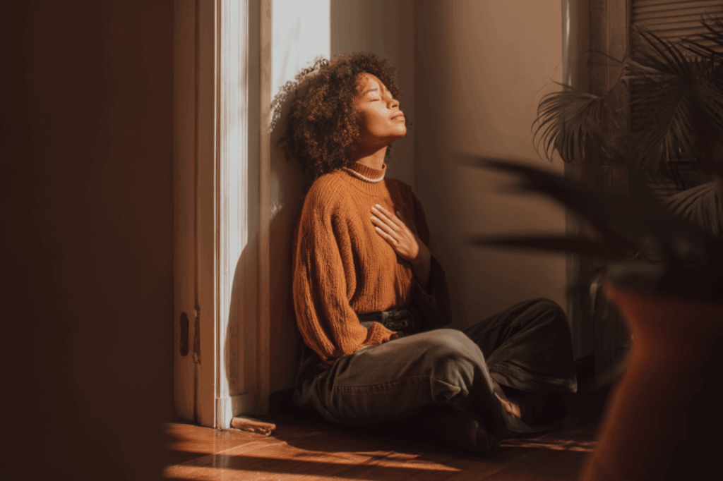 Person sitting peacefully by a window, reflecting and grounding themselves during early recovery after leaving rehab